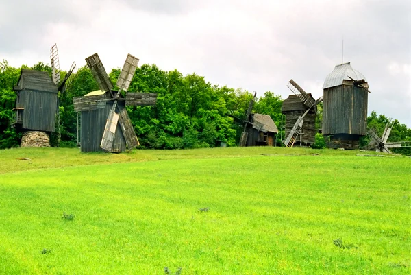 Wooden mills on the field of green grass. — Stock Photo, Image