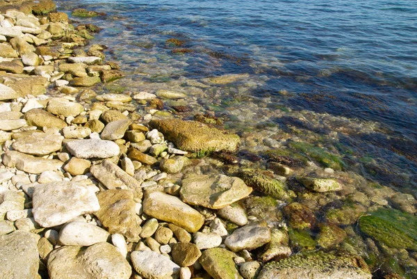Eine Küste mit Kieselsteinen und blauem Meerwasser. — Stockfoto