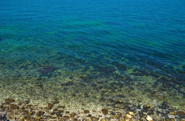 Pobřeží s kameny a modrý oceán vody. — Stock fotografie