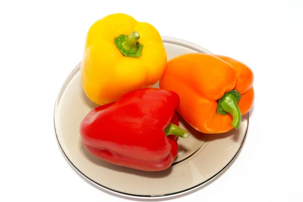 Tre fargede paprika på tallerkenen på hvit bakgrunn . – stockfoto