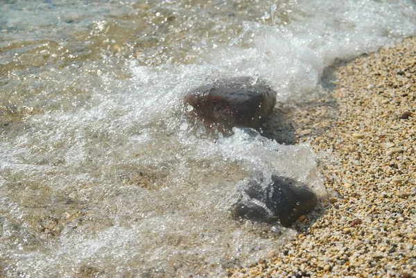 Vallende stenen in de golven en de zee schuim. — Stockfoto
