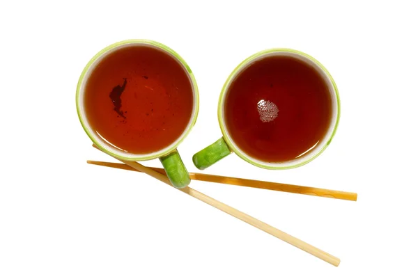 Two teacups with tea and chopsticks isolated on white. — Stock Photo, Image