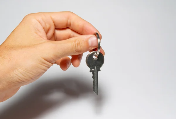 Silver key in a hand on gray background. — Stock Photo, Image