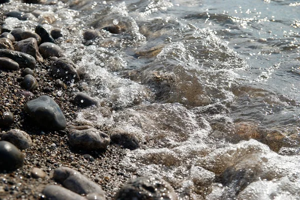 Vallende stenen in de golven en de zee schuim. — Stockfoto