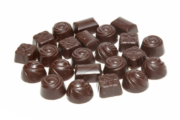 Lahodné tmavé čokoládové pralinky izolované na bílém. — Stock fotografie