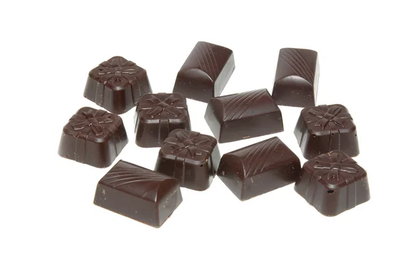 Lahodné tmavé čokoládové pralinky izolované na bílém. — Stock fotografie