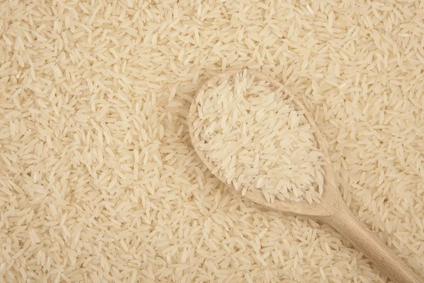 Holzlöffel mit Reis isoliert auf Reishintergrund — Stockfoto