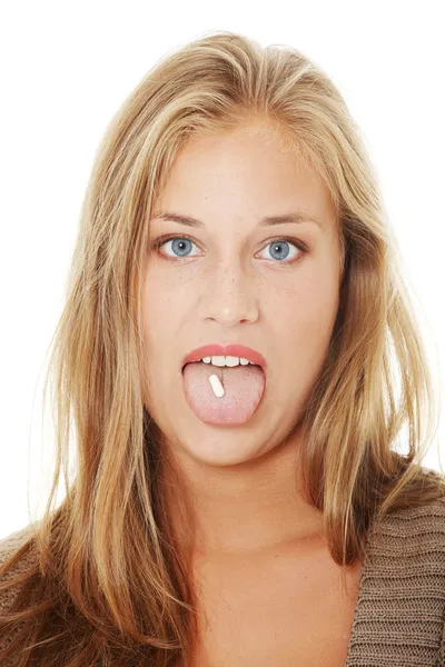 Young woman with pill in her mouth Royalty Free Stock Photos