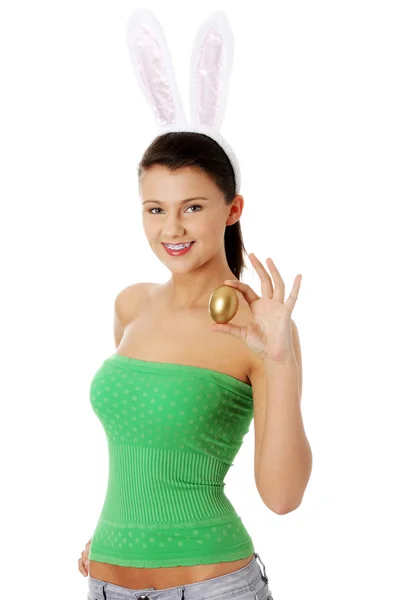 Young girl with bunny ears holding golden egg — Stock Photo, Image