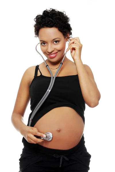 Mujer embarazada escuchando su vientre con estetoscopio — Foto de Stock