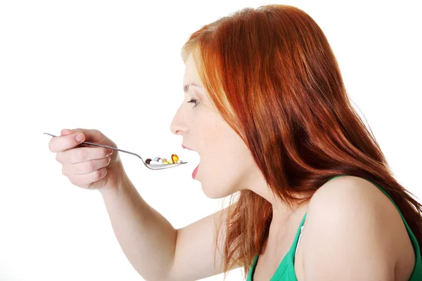 Teen girl taking pills from spoon. — Stock Photo, Image