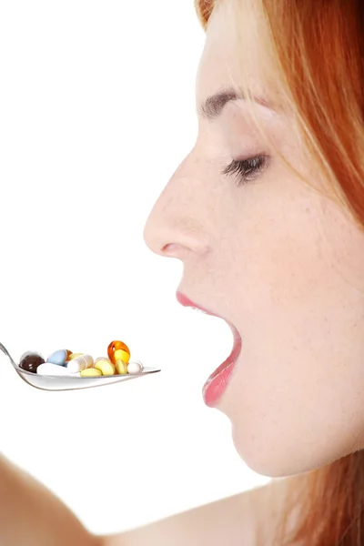 Teen girl taking pills from spoon. — Stockfoto