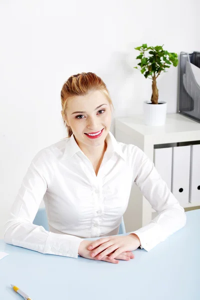 Mulher sorridente sentada atrás da mesa em seu escritório . — Fotografia de Stock