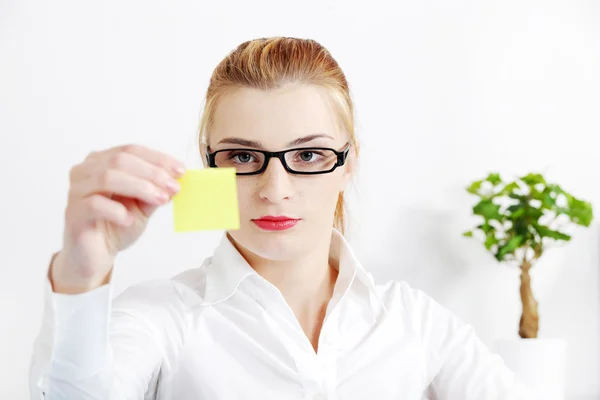 Businessfrau betrachtet gelbes Blatt Papier. — Stockfoto