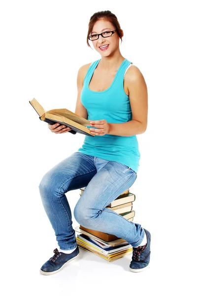 Young girl sitting on books and smiling. — Stock Photo, Image