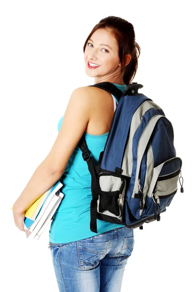 Dospívající dívka s poznámkami, usmíval se a ukazuje její batoh. — Stock fotografie