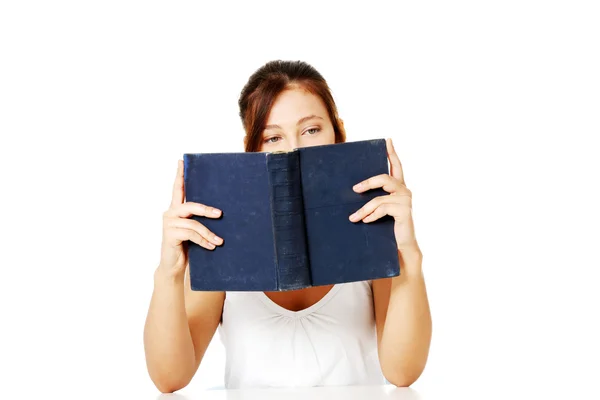 Mädchen liest und versteckt sich hinter dem Buch. — Stockfoto