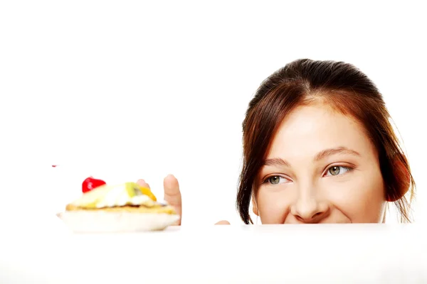 stock image Girl hiding behind the desk and reaching for the cake.