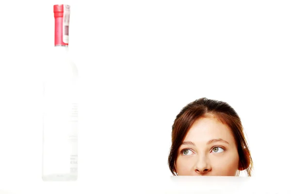 Young girl looking at the bottle. — Stock Photo, Image