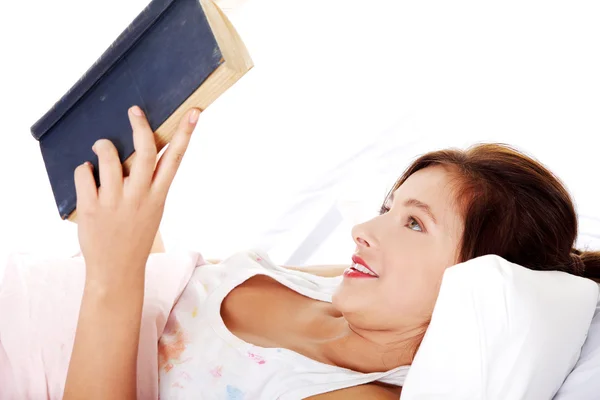 十代の少女がベッドで本を読んで. — ストック写真