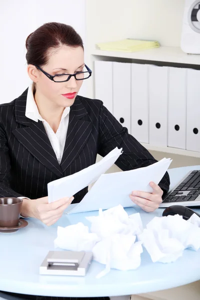 Businesswoman reading files near crumpled files. — Stock Photo, Image