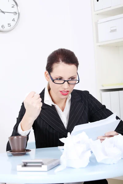 Angry businesswoman reading files near crumpled files. — Stok fotoğraf