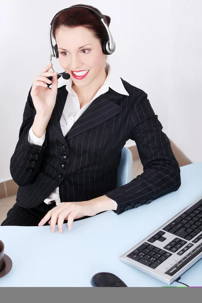 Smuk forretningskvinde taler gennem hovedtelefonerne . - Stock-foto