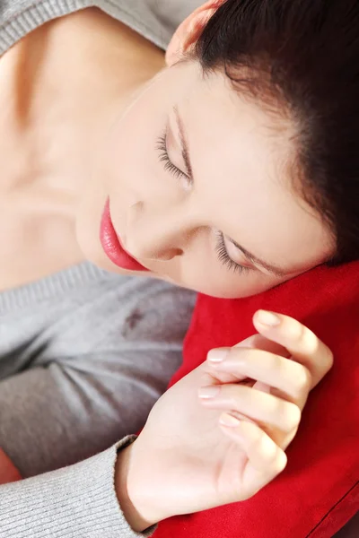 Slapende vrouw liggend op een rode kussen. — Stockfoto