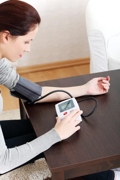 Jovem mulher medir sua pressão arterial em casa . — Fotografia de Stock