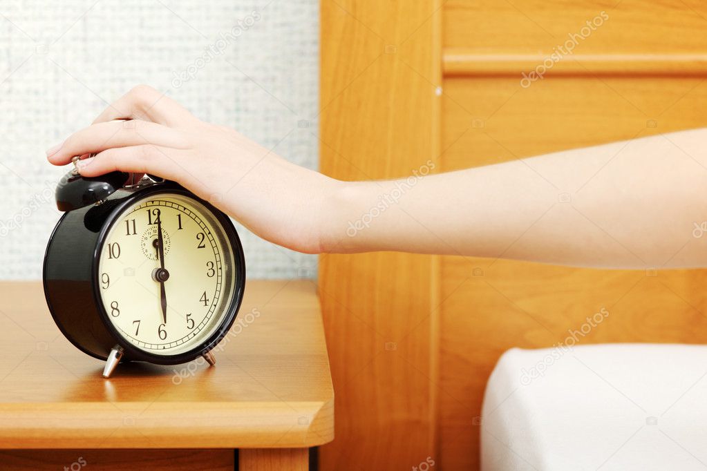 Woman turning off the alarm clock in the morning.