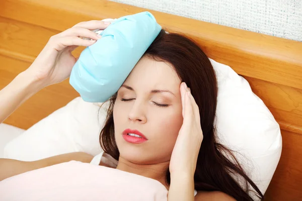 Suffering woman with an ice-bad on her head. — Stock Photo, Image