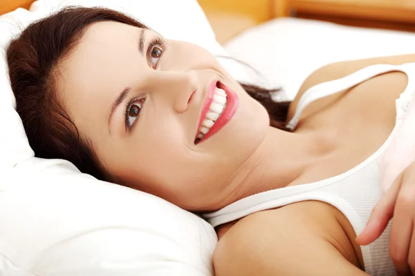 Schöne junge Frau ruht sich im Bett aus. — Stockfoto
