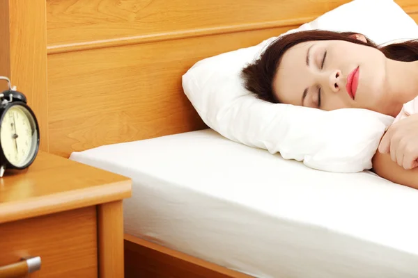 Mujer dormida con un despertador al lado de la cama . —  Fotos de Stock