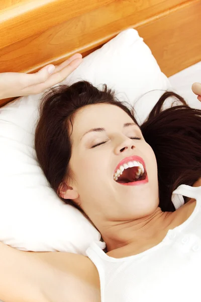 Hermosa mujer bostezando y estirando su cuerpo en la cama . — Foto de Stock