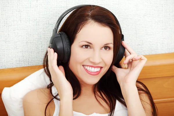 Mulher bonita ouvindo música através dos fones de ouvido . — Fotografia de Stock