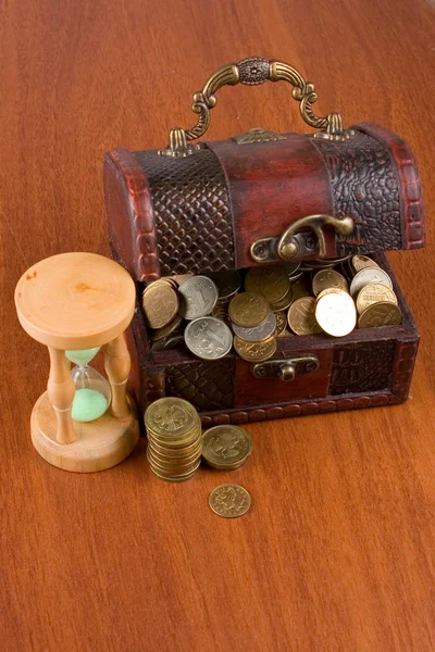 Pecho abierto con monedas y reloj de arena — Foto de Stock