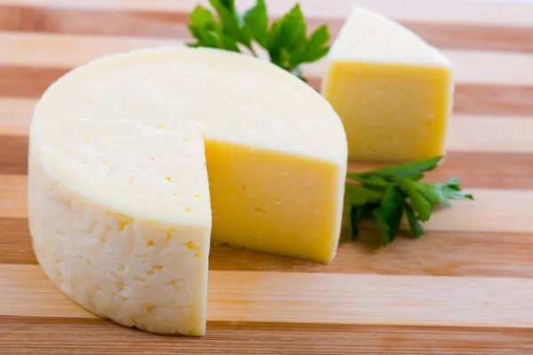 Ahşap tahta üzerinde yuvarlak peynir — Stok fotoğraf