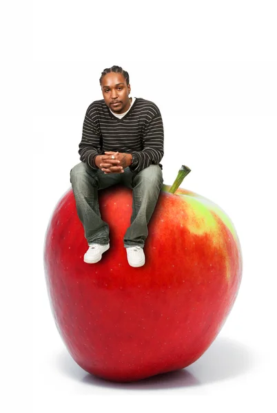 Чоловік сидить на червоному смачному яблуці — стокове фото