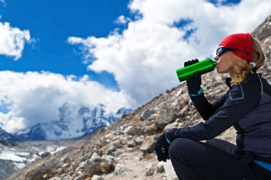 Woman drinking in mountains clipart