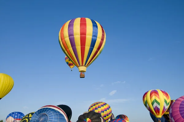 Hot-air balloons ascending over inflating ones — Stock Photo, Image