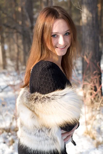 Jeune fille dans un gilet de fourrure dans les bois enneigés — Photo