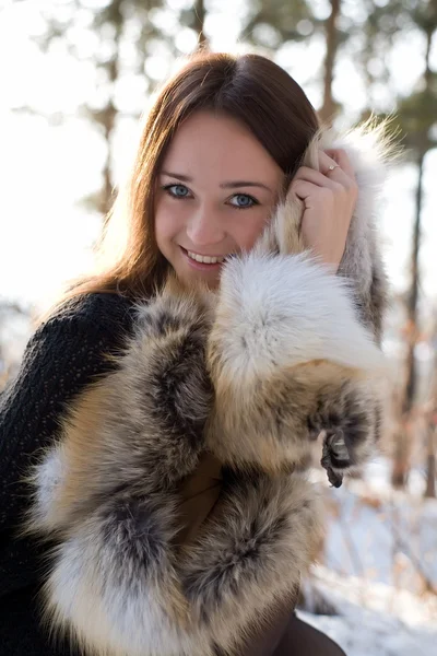 Young girl in a fur vest in snowy woods — Stock Photo, Image