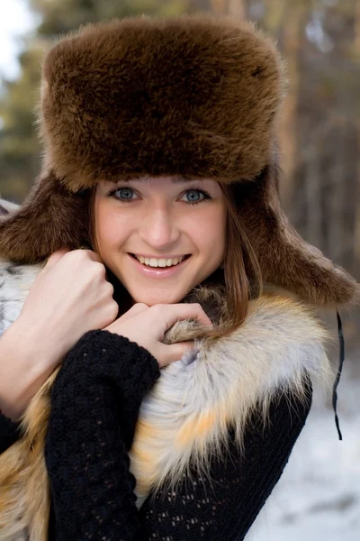 Junges Mädchen in einer Fellweste im verschneiten Wald — Stockfoto