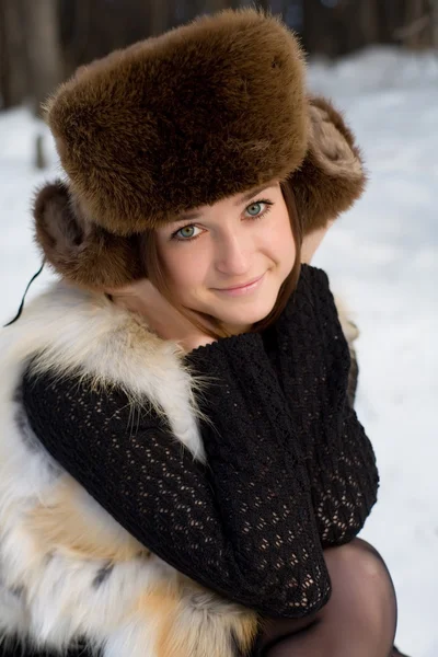 Молодая девушка в меховом жилете в снежных лесах — стоковое фото