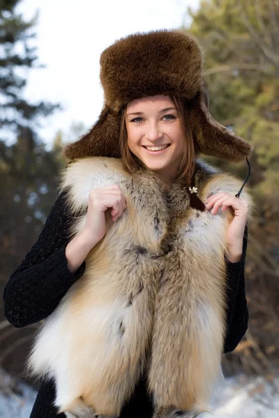 Молодая девушка в меховом жилете в снежных лесах — стоковое фото