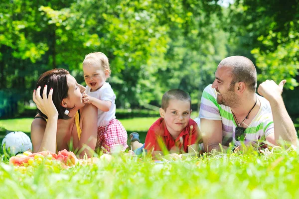 Szczęśliwa młoda para z dziećmi zabawy w parku — Zdjęcie stockowe