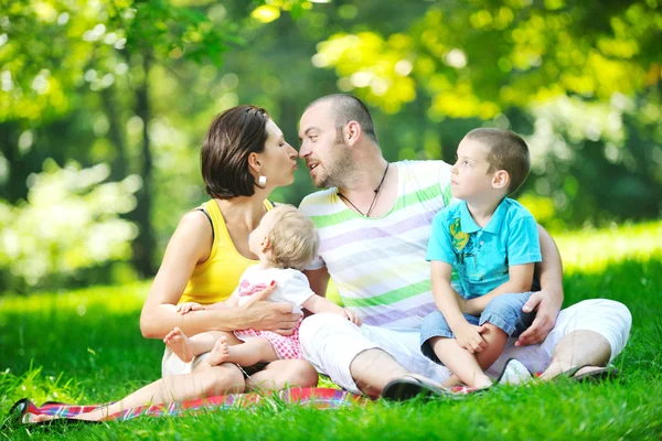 Feliz jovem casal com seus filhos se divertir no parque — Fotografia de Stock