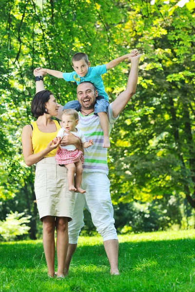 Щаслива молода пара зі своїми дітьми розважається в парку — стокове фото