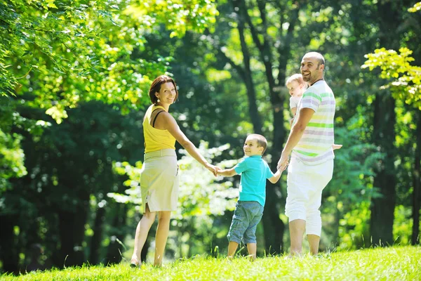 Glückliches junges Paar mit ihren Kindern hat Spaß im Park Stockbild