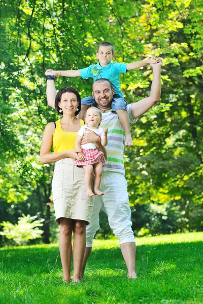 Счастливая молодая пара с детьми развлекается в парке Стоковая Картинка